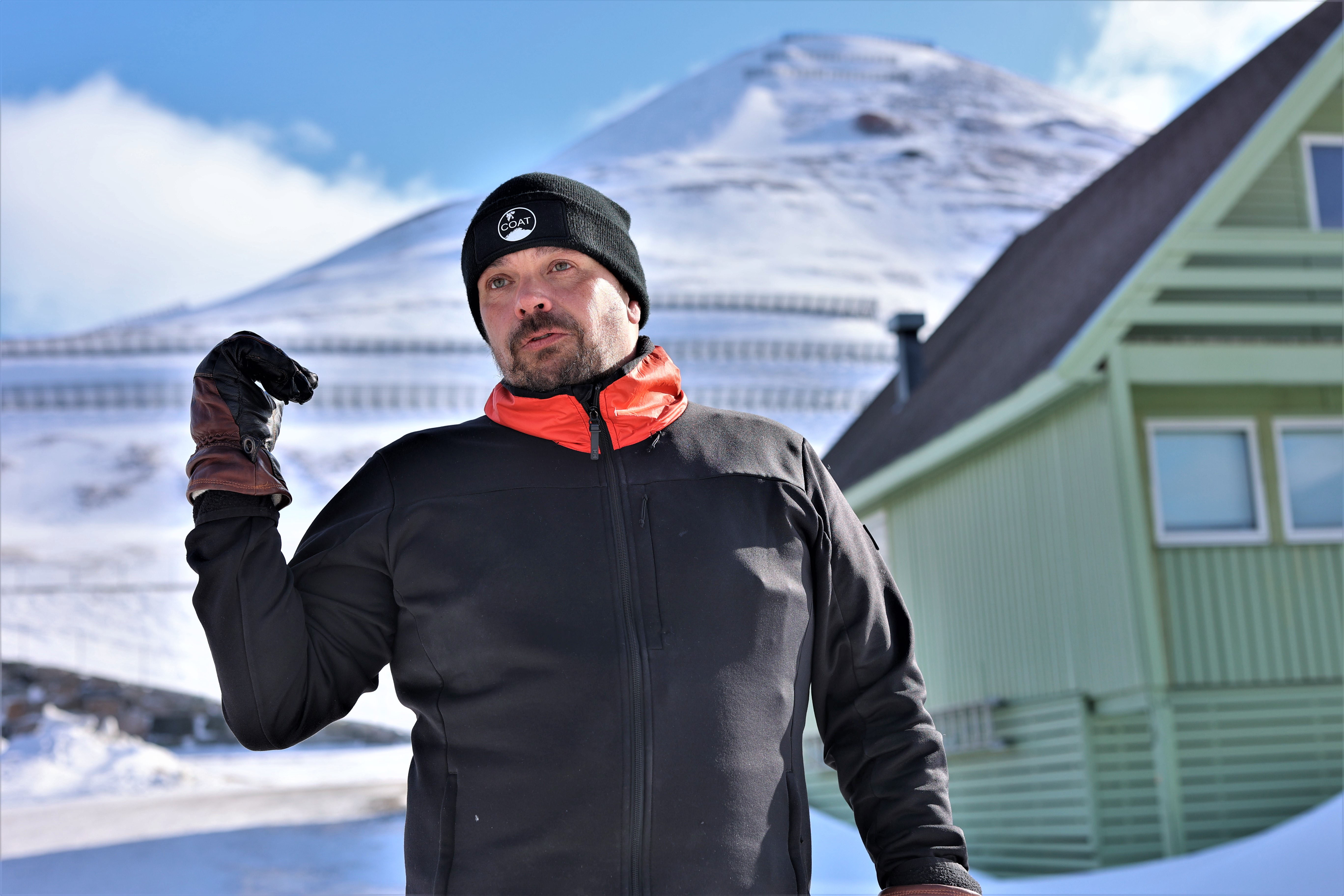 Man pointing backwards to a mountain in the background